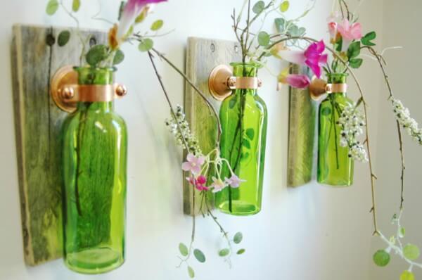 Garrafas verdes de vidro com plantas em ambiente fechado