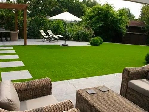 Jardim decorado com mesa, banco e cadeiras.